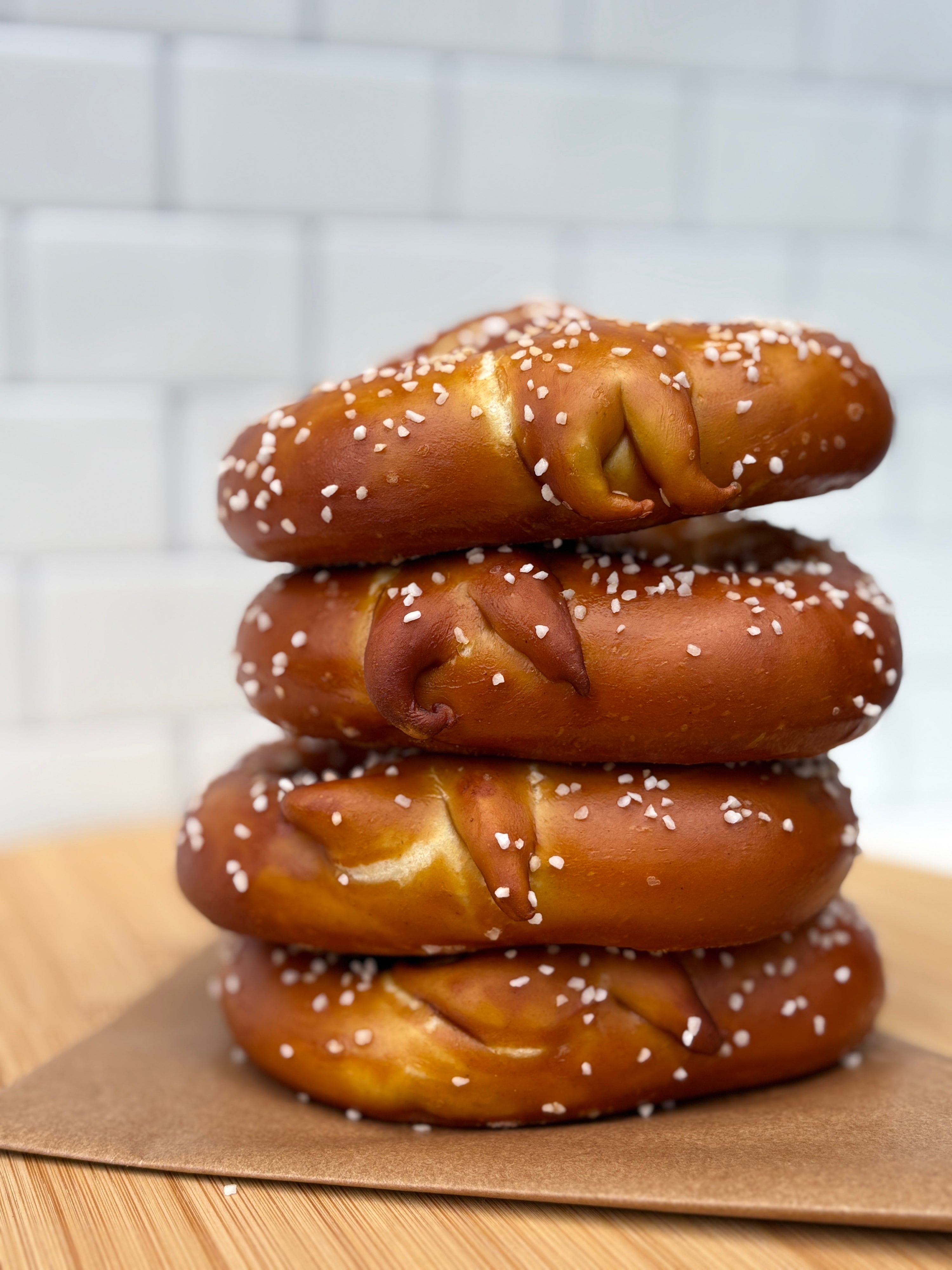 Stack of pretzels on a wooden surface with a tiled wall background