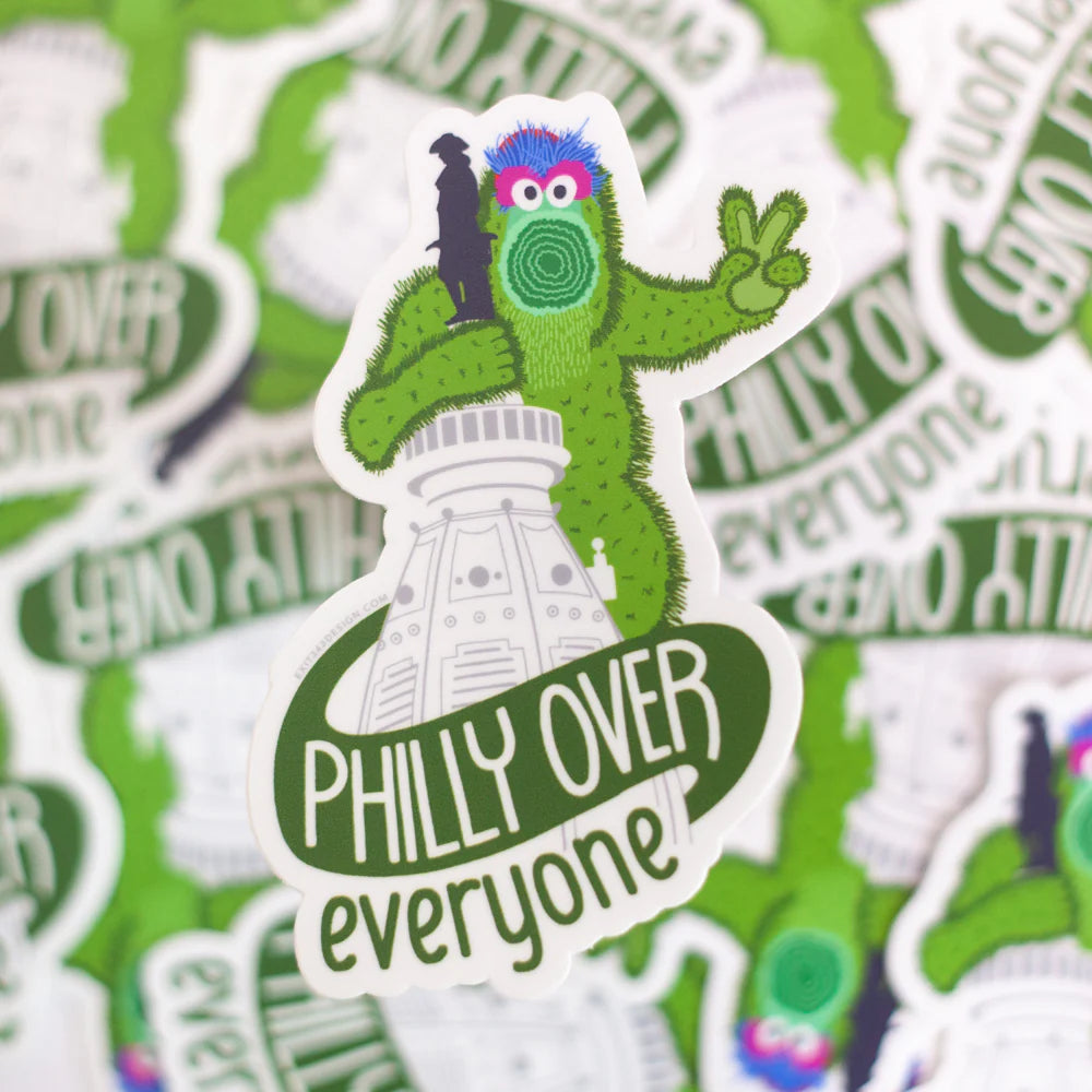 Sticker with a green creature on top of a building with 'Philly Over Everyone' text, surrounded by similar stickers.
