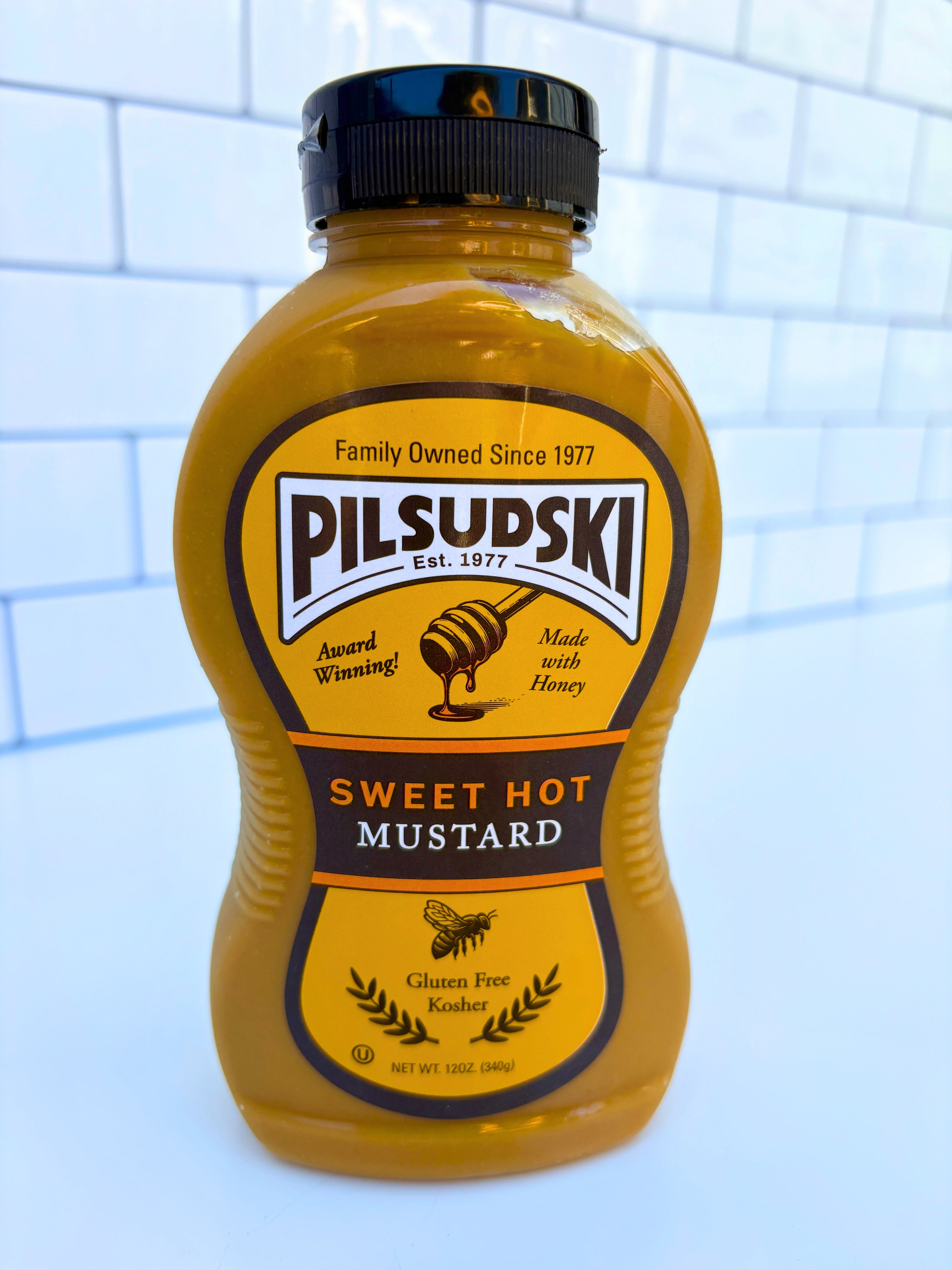 Bottle of Pilsudski Sweet Hot Mustard on a tiled wall background