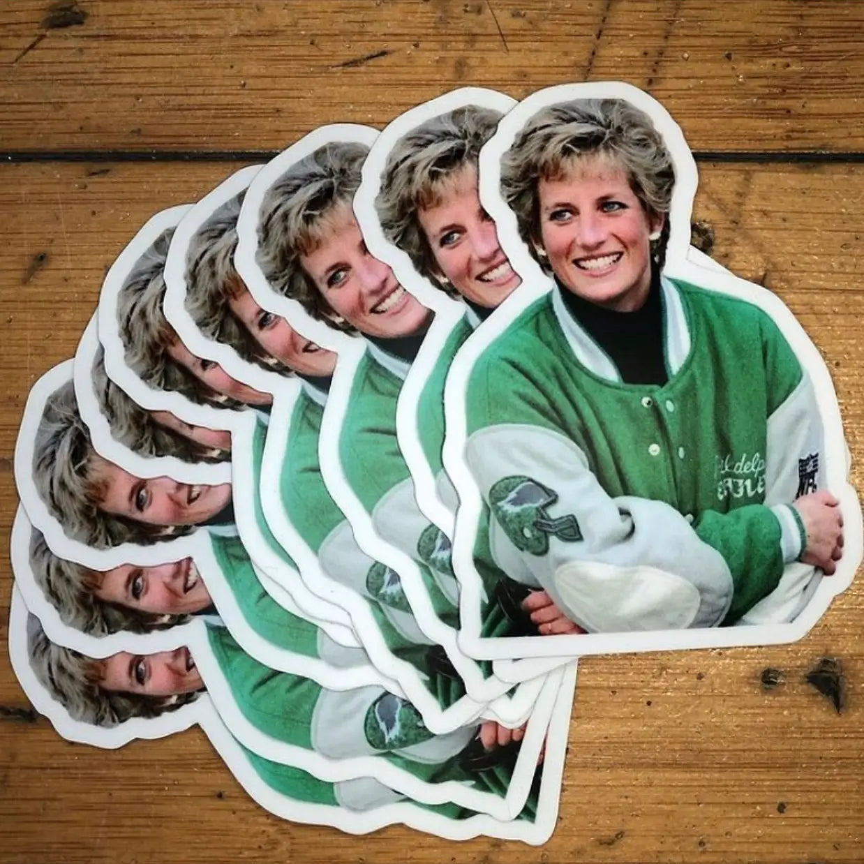 Stack of stickers with a person in a green jacket on a wooden surface